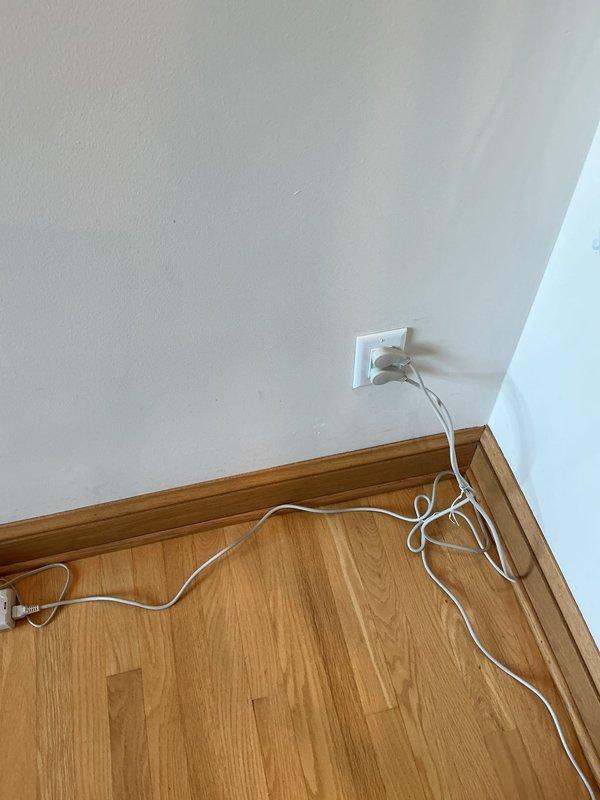 Installed dedicated electrical outlet for stairlift operation in residential interior corner location. Outlet was mounted on wall above baseboard molding to provide accessible power supply for mobility equipment, with installation completed after 10 AM per customer notification timing.