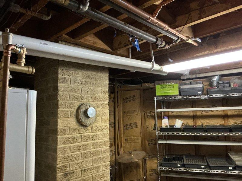 Successfully completed installation of combination boiler system with four-zone hydronic heating distribution. Installed comprehensive copper piping network with multiple blue-handled ball valves for zone isolation, black distribution manifolds with brass fittings, and gray expansion tank for system pressure management. Mounted all components to interior wall studs during rough-in phase, incorporating stainless steel flexible connectors and proper valve placement throughout. Staged and integrated condensate pump with tubing, complete boiler kit, and all necessary mounting hardware. Installed REHAU PEX piping runs across ceiling joists with proper hangers and brackets, connecting to existing infrastructure. All zones properly manifolded and valved for independent temperature control, with system ready for insulation and finish work.