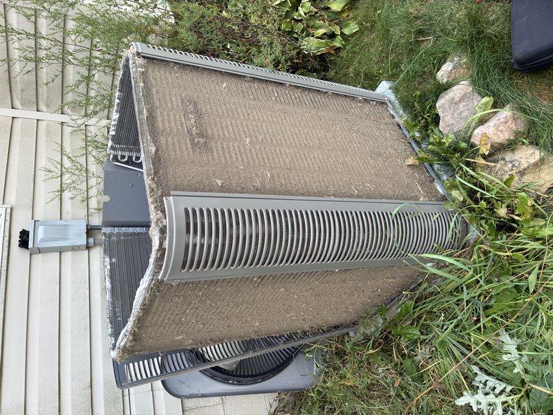 Completed MVP cooling maintenance visit on 2-year-old system. Inspected outdoor condensing unit, noting weathered top panel with dirt and organic matter accumulation on exterior surfaces. Examined condenser coil fins for debris and airflow restrictions. Evaluated indoor ductwork and refrigerant lines in attic space, observing dust buildup on metal duct surfaces and aged copper refrigerant piping with normal patina. Documented system condition through photography for maintenance records.