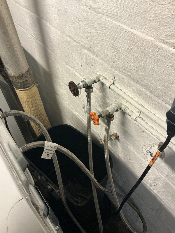 Installed new ball valve with orange handle on water supply line in basement utility area. Replaced existing valve assembly and connected braided stainless steel flexible supply hoses to ensure proper water flow control. System tested and verified operational with no leaks detected.