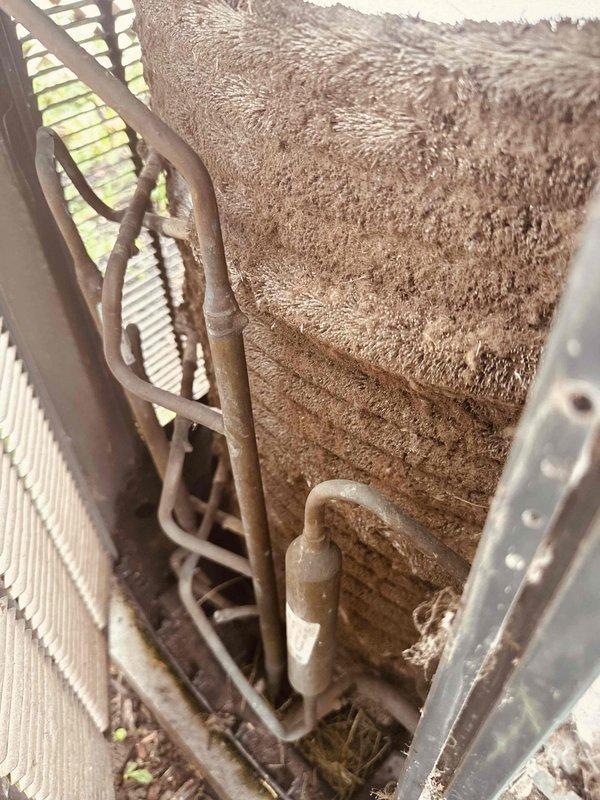 Responded to service call for 16-year-old Trane central air conditioning system that had lost cooling capacity and was only producing temperate air. Upon inspection, found dual critical issues: severely deteriorated dual-run capacitor showing extensive rust, corrosion, and weather damage with compromised connections, and evaporator coils heavily caked with dust and debris accumulation restricting airflow. Replaced failed capacitor with new OEM-equivalent component and performed thorough coil cleaning to remove thick layer of contamination. Restored proper electrical values, verified adequate airflow across coils, and tested system operation with satisfactory cooling performance and temperature differential.