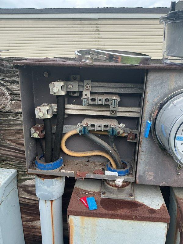 Performed comprehensive inspection of exterior electrical meter base and service equipment to facilitate utility power restoration. Documented extensive corrosion and weathering on meter panel enclosure, internal bus bars, and terminal connections. Assessed condition of service entrance conductors, mounting hardware, and multiple meter installations showing significant age-related deterioration requiring attention for code compliance and safe operation.