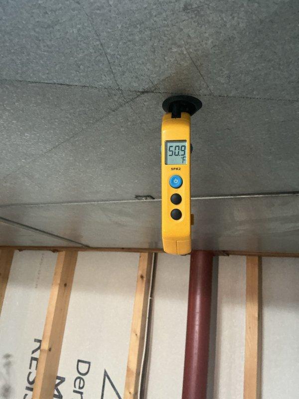 Responded to complaint of loud noise from AC unit. Performed diagnostic assessment and took temperature measurements at ceiling level registering 50.9°F, indicating proper cooling function. Inspected accessible components and documented conditions for service records.