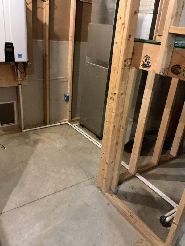 Removed existing 40-gallon power vent water heater and installed new Navien NPE-240A2 tankless water heater. Unit was wall-mounted on plywood backing near original tank location with all necessary supply and return piping reconfigured using copper pipe and PEX connections. Gas line was replumbed to accommodate new unit specifications, condensate drain line was routed to floor drain, and exhaust/intake air lines were installed with termination on south exterior wall near gas meter. Installation includes 12-year heat exchanger warranty, 5-year parts warranty, and 1-year labor warranty.