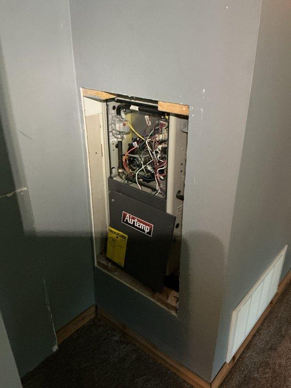 Completed full HVAC system installation including indoor Airtemp wall-mounted air handler and outdoor condensing unit. The indoor unit was installed in a recessed wall cavity with proper electrical connections, refrigerant line set, and condensate drainage. The outdoor condenser was positioned on a gravel pad against the exterior brick wall with appropriate clearances, connected to a wall-mounted electrical disconnect box, and linked to the indoor unit via copper refrigerant lines and PVC condensate piping. System was tested and verified operational.