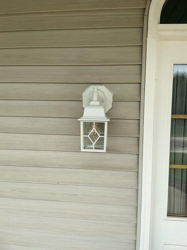 Performed site evaluation for replacement of nine exterior light fixtures. Identified four garage-mounted fixtures lacking proper electrical boxes and front-mounted fixtures with protruding pan boxes incompatible with flush installation of new fixtures. Recommended and will install nine Arlington siding blocks to ensure proper mounting and flush appearance. Will replace all nine customer-supplied lantern-style fixtures with appropriate electrical boxes where missing, removing existing siding blocks and installing new weatherproof mounting solutions for code-compliant, aesthetically consistent installation across all exterior locations.