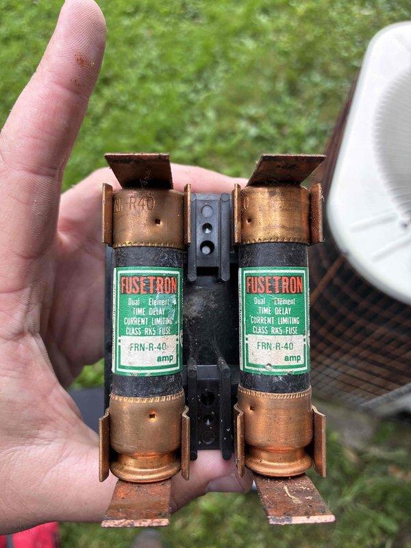Completed MVP cooling maintenance on outdoor AC unit. Inspected and documented dual-element 40-amp FRN-R fuses in disconnect, which were functional but showing age-related discoloration. Found significant rust and corrosion on air handler components with accumulated debris including leaves and organic matter inside ductwork, indicating moisture intrusion and potential drainage issues requiring future attention.