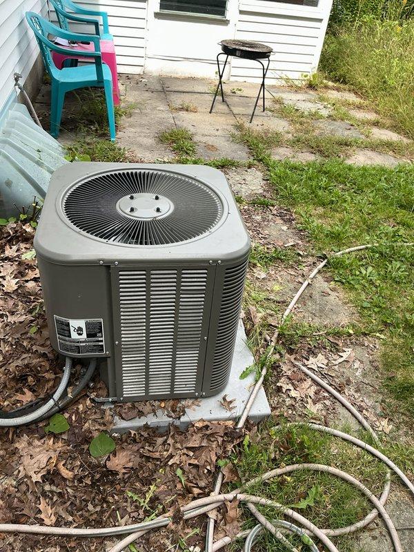 Responded to service call for Lennox air conditioning condenser unit experiencing water leakage from side panels and seams. Performed visual inspection of outdoor condenser unit and surrounding area, documenting unit condition and installation setup. Photographed equipment for service records showing unit placement on concrete pad with electrical disconnect properly mounted on exterior wall.