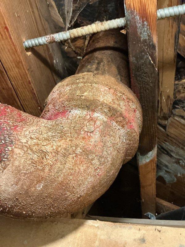 Responded to main bathroom for clogged toilet with suspected wax ring leak. Upon inspection, found toilet bowl heavily soiled with significant staining and accumulation in drain opening. Assessed underlying plumbing infrastructure in crawl space, noting severely corroded cast iron waste pipe with extensive rust and mineral deposit buildup on drainage system. Cleared toilet obstruction and evaluated wax ring seal at base where discoloration indicated potential leak point. Documented existing conditions of deteriorated waste line and recommended monitoring for future replacement due to advanced pipe corrosion that could contribute to ongoing drainage issues.