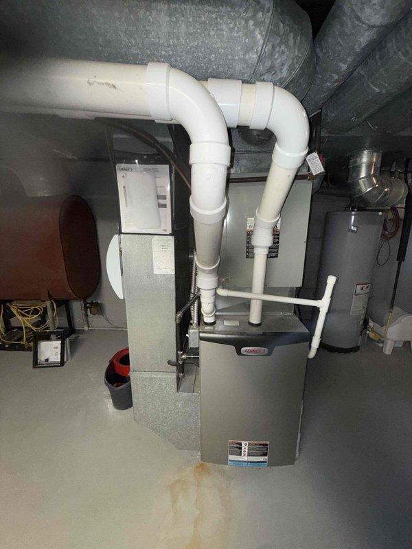 Completed comprehensive MVP AC maintenance on Trane XV series air conditioning system. Performed visual inspection of outdoor condenser unit, verifying proper operation of compressor and condenser fan, checking refrigerant lines for leaks or damage, and cleaning debris from unit exterior and grille. Inspected indoor furnace and evaporator coil assembly in basement mechanical room, examined condensate drain system with PVC piping configuration for proper drainage and clearing any blockages, verified airflow through ductwork, and checked electrical connections at both indoor and outdoor units. System tested and operating within normal parameters upon completion of maintenance service.