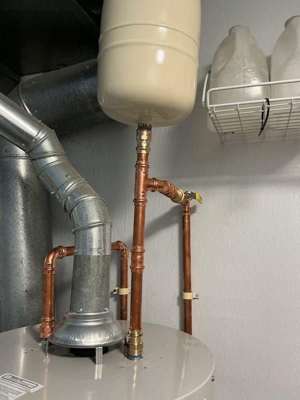 Relocated expansion tank away from laundry sink area to improve customer accessibility and safety after reports of head contact with the unit. Repositioned tank to side wall using existing truck stock materials, reconnected all copper piping with appropriate fittings, and verified system pressure and operation upon completion.