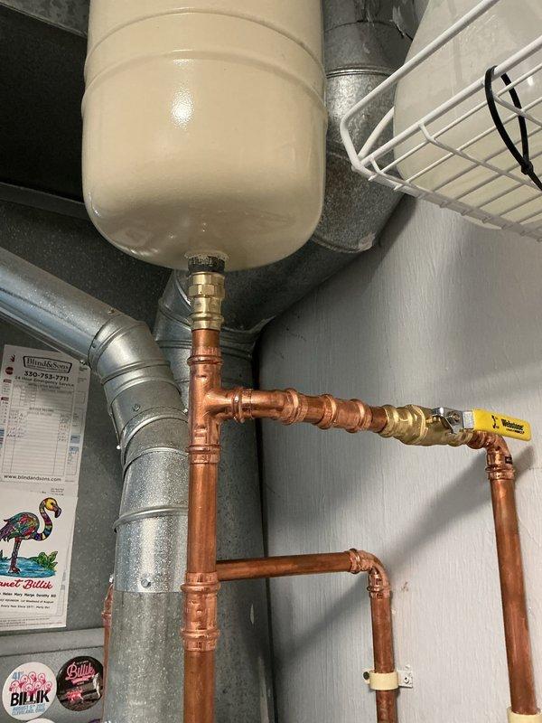 Relocated expansion tank away from laundry sink area to improve customer accessibility and safety after reports of head contact with the unit. Repositioned tank to side wall using existing truck stock materials, reconnected all copper piping with appropriate fittings, and verified system pressure and operation upon completion.
