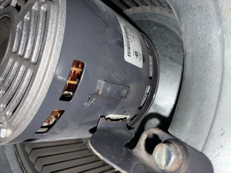 Responded to service call for loud noise coming from HVAC blower motor in 10-year-old furnace unit located in basement. Upon inspection, discovered significant crack in blower motor housing and exposed copper windings indicating motor failure. Documented damage with photographs showing compromised motor casing, visible electrical connections, and wire assembly. Diagnosed failed blower motor as source of reported noise and recommended replacement to restore proper system operation.