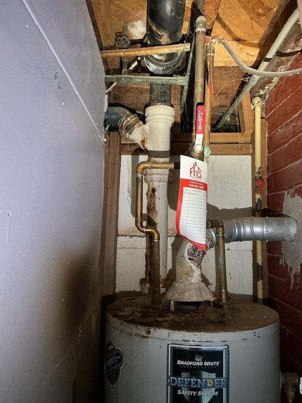 Completed free estimate for tanked water heater replacement. Inspected existing Bradford White Defender Safety System unit installed in basement utility area. Unit exhibited significant age-related deterioration including rust staining on top surface and around base, moisture staining on surrounding floor area, and general wear on tank exterior. Evaluated all plumbing connections including copper supply lines, PVC venting, brass fittings, and valve assemblies extending from top of unit. Assessed installation environment including exposed brick walls, wooden framing, and clearance requirements for replacement. Documented current water heater condition and configuration through photographs for estimate preparation. Accessed property using provided lockbox code at rear of residence.