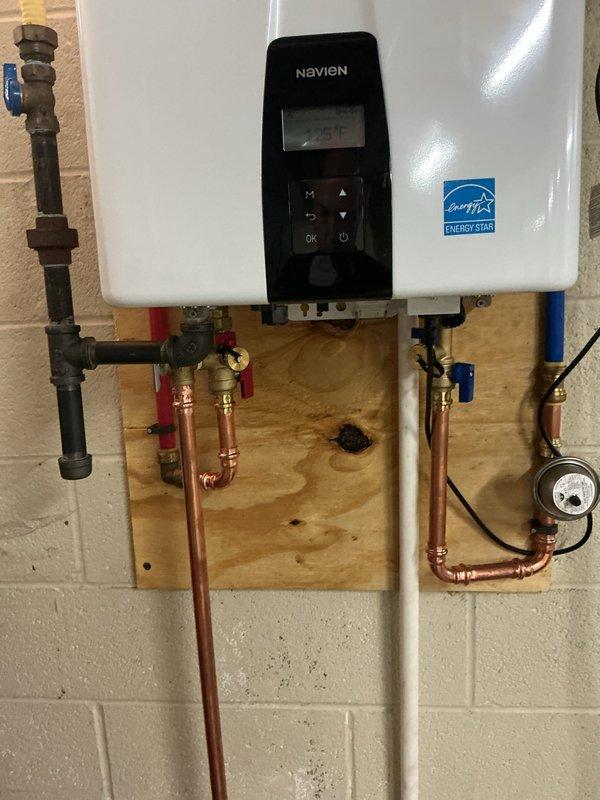 Replaced existing Rinnai tankless water heater with new Navien NPE-240 model. Installation included new service valves on hot and cold water lines, copper piping connections with brass fittings, and replacement of exhaust venting system with new PVC pipe and elbows routed through exterior wall. Unit mounted on wooden backing board in utility area, programmed to 125°F, and tested for proper operation.