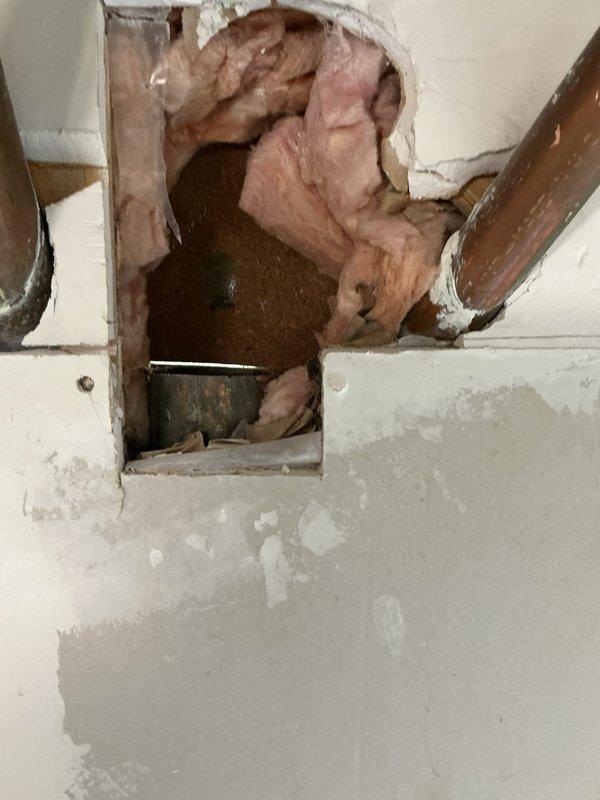 Removed and replaced defective copper double sanitary tee serving back-to-back toilet configuration. Pulled master bathroom toilet and cut open hall bathroom wall to access existing drain and vent stack. Removed horizontal copper piping from kitchen wall connection through both toilet flanges. Installed new 3" PVC drainage system including two new toilet flanges connected to double wye fitting for back-to-back toilet waste lines, then reconnected to existing copper line at kitchen wall. New piping installed at slightly lower elevation than original configuration.