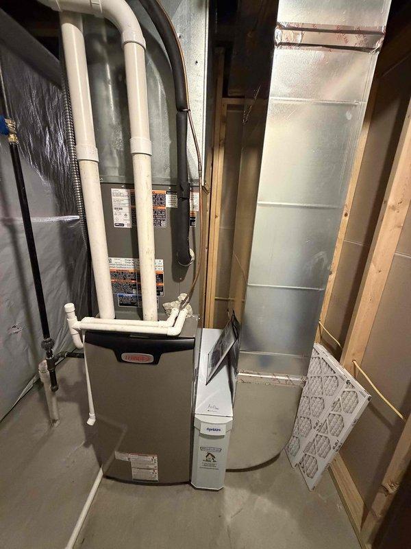 Completed installation of new Lennox high-efficiency furnace system in basement utility area. Installed and configured primary heating unit with proper venting using white PVC intake and exhaust piping routed vertically from unit top. Connected metal supply ductwork with insulated sections and installed aluminum flex duct connections. Positioned air filtration media and verified all manufacturer specifications and safety labels are visible and compliant. System installation represents first phase of complete HVAC upgrade, with unit now operational at 90% completion pending final connections and commissioning.