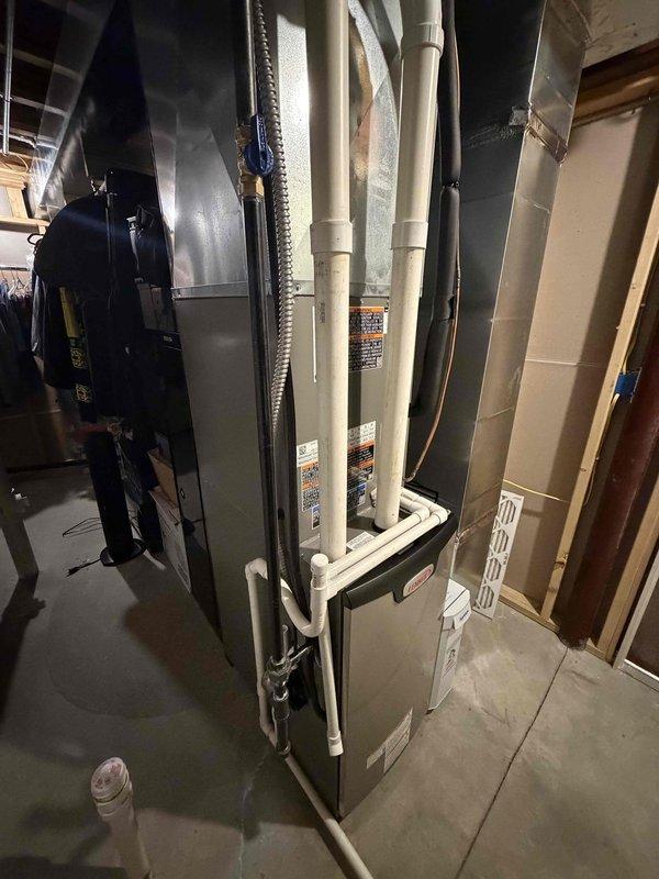 Completed installation of new Lennox high-efficiency furnace system in basement utility area. Installed and configured primary heating unit with proper venting using white PVC intake and exhaust piping routed vertically from unit top. Connected metal supply ductwork with insulated sections and installed aluminum flex duct connections. Positioned air filtration media and verified all manufacturer specifications and safety labels are visible and compliant. System installation represents first phase of complete HVAC upgrade, with unit now operational at 90% completion pending final connections and commissioning.