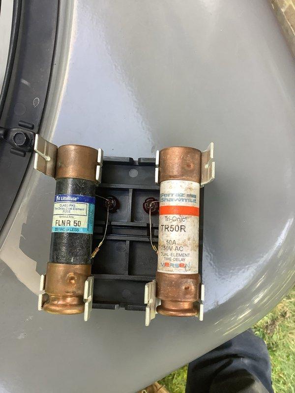 Relocated air conditioning unit to new position on concrete pad against building exterior. Installed dual-element time-delay fuses (50-amp rated) in outdoor disconnect for proper circuit protection, coordinating with electrical contractor for circuit completion. Unit positioned on level pad with proper clearances maintained for airflow and service access.