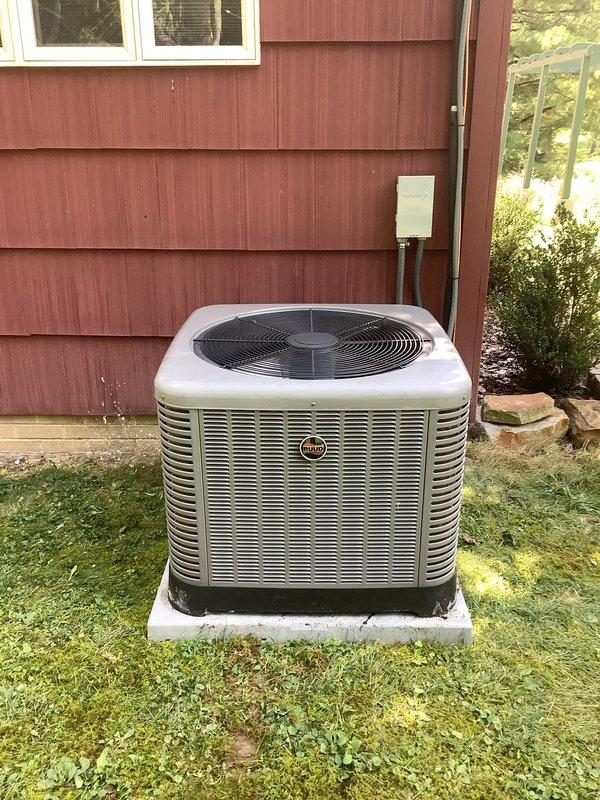 Relocated air conditioning unit to new position on concrete pad against building exterior. Installed dual-element time-delay fuses (50-amp rated) in outdoor disconnect for proper circuit protection, coordinating with electrical contractor for circuit completion. Unit positioned on level pad with proper clearances maintained for airflow and service access.