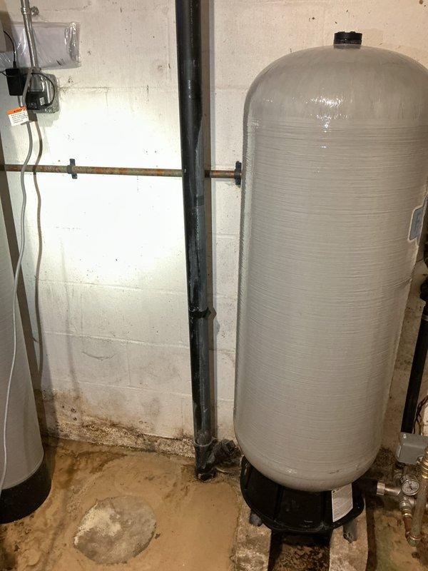 Responded to water backup from basement floor drain. Upon arrival, inspected basement plumbing system including pressure tank, piping connections, and drainage system. Identified water accumulation on concrete floor around plumbing equipment and floor drain area. Assessed main drain line and pressure tank installation for potential blockage or system malfunction causing water to back up through basement drain. Cleared obstruction and verified proper drainage flow restored to prevent further water intrusion into basement.