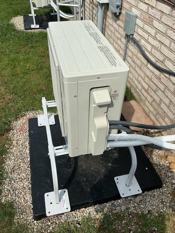 Responded to service call for recently installed ductless mini-split system where outdoor unit cover was improperly secured following electrical rewiring during initial installation. Inspected outdoor condenser unit mounted on stand with rubber pad, verified refrigerant line connections and electrical conduit routing along building exterior, properly reinstalled and secured unit cover panel to manufacturer specifications, and documented completed work with photographs.