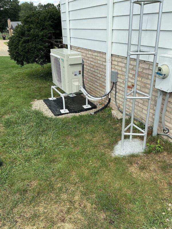 Responded to service call for recently installed ductless mini-split system where outdoor unit cover was improperly secured following electrical rewiring during initial installation. Inspected outdoor condenser unit mounted on stand with rubber pad, verified refrigerant line connections and electrical conduit routing along building exterior, properly reinstalled and secured unit cover panel to manufacturer specifications, and documented completed work with photographs.