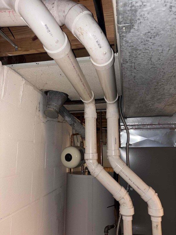 Corrected exhaust venting system by rerunning PVC exhaust pipes in proper configuration per code requirements. Installed new vertical PVC vent runs with appropriate 90-degree elbows and secured all piping with proper mounting straps. Documented completed installation with photographs for municipal reinspection approval.