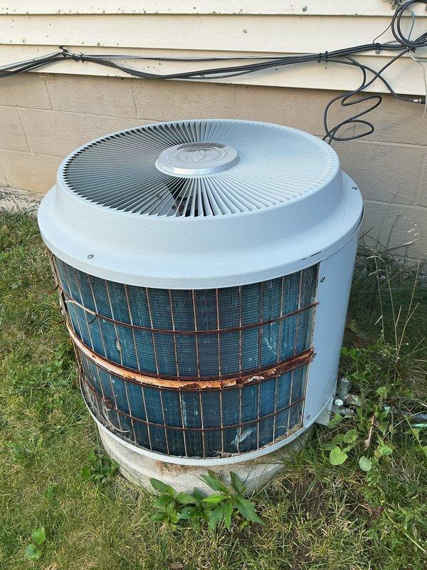 Responded to service call for 15-year-old central air conditioning system not cooling the house. Upon arrival, performed comprehensive system inspection of both indoor and outdoor components. Examined outdoor condenser unit showing significant age-related wear, including rust formation on exterior casing and around mid-section of unit. Inspected condenser coils for proper airflow and debris accumulation. Evaluated indoor air handler and ceiling-mounted fan assembly, checking motor housing, electrical connections, and refrigerant lines. Verified all wiring connections were secure and assessed overall system operation to diagnose cooling deficiency and restore proper functionality.