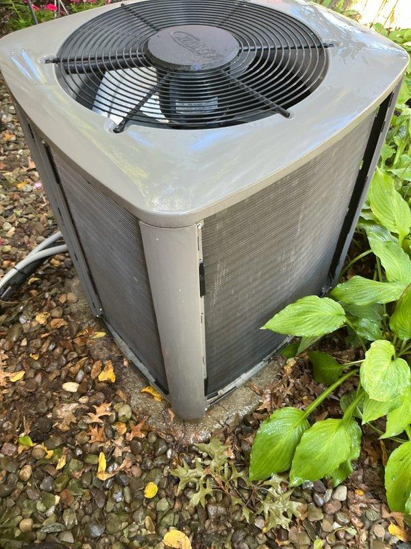 Completed comprehensive MVP air conditioning maintenance on residential outdoor condenser unit. Performed thorough inspection of cabinet, fan assembly, and protective grille, confirming proper operation of axial fan motor and secure mounting of all components. Verified unit positioning on concrete pad with adequate clearance from surrounding vegetation and landscaping. Inspected electrical conduit, refrigerant lines, and PVC condensate drainage system for proper installation and functionality. Cleaned exterior surfaces, removing accumulated dirt, debris, and organic matter from cabinet panels and gravel base area. Confirmed adequate airflow through louvered side panels and verified all safety guards and protective components are secure and in good working condition.