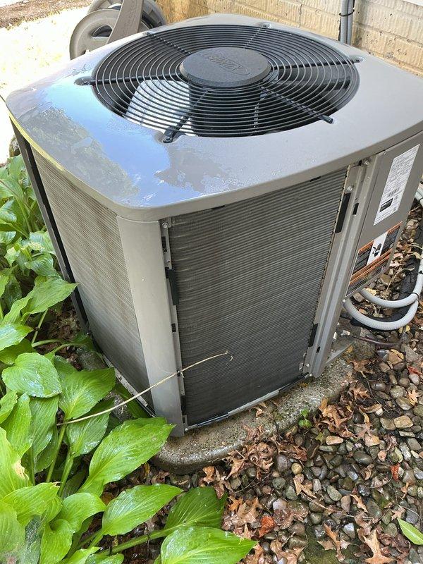 Completed comprehensive MVP air conditioning maintenance on residential outdoor condenser unit. Performed thorough inspection of cabinet, fan assembly, and protective grille, confirming proper operation of axial fan motor and secure mounting of all components. Verified unit positioning on concrete pad with adequate clearance from surrounding vegetation and landscaping. Inspected electrical conduit, refrigerant lines, and PVC condensate drainage system for proper installation and functionality. Cleaned exterior surfaces, removing accumulated dirt, debris, and organic matter from cabinet panels and gravel base area. Confirmed adequate airflow through louvered side panels and verified all safety guards and protective components are secure and in good working condition.