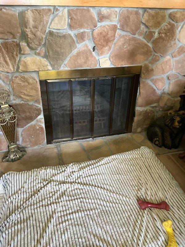 Completed gas line installation to existing stone fireplace to convert from wood-burning to gas operation. Ran new gas supply line from existing source to fireplace location, installed appropriate shutoff valve and connection point for future gas log insert installation. Fireplace features natural stone surround with existing metal screen door that will accommodate gas log conversion upon equipment installation.