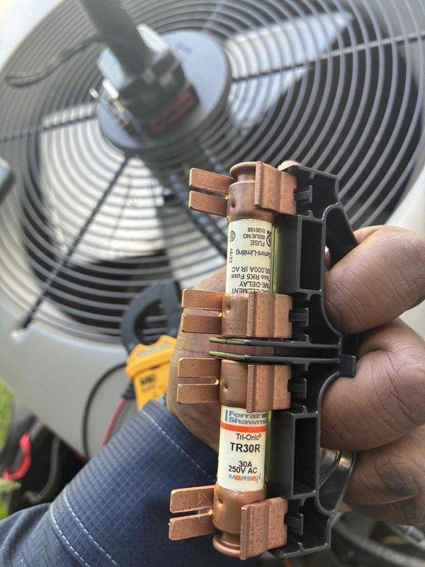 Completed MVP cooling maintenance visit on residential outdoor condensing unit. Inspected condenser coil fins which showed normal weathering and some dirt accumulation, verified proper clearance from surrounding vegetation and confirmed unit was level on concrete pad. Examined and documented electrical components including 30-amp TR30R time-delay fuses rated at 250V AC, which were found in serviceable condition. Inspected condenser fan motor and housing for proper operation and structural integrity.