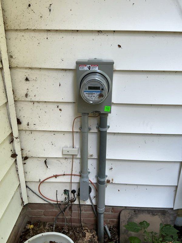 Installed new 100 amp meter base and disconnect on exterior service entrance. Modified PVC riser by cutting down and installing expansion coupling for proper clearance. Installed new grounding system with ground rods and verified existing waterline ground connection to panel. Established supplemental bonding by connecting to accessible copper piping in ceiling near tankless water heater, as unit is primarily served by PEX plumbing. Installed bonding jumpers around water softener system to maintain grounding continuity. Ran new 3-wire feeder circuit to main panel with PVC conduit protection along exterior wall within driveway proximity zone per code requirements. Corrected breaker compatibility issues in main panel by replacing incompatible tandem Siemens breaker with proper single-pole breaker and installing additional breaker in available space below. Removed incorrectly installed GE breaker and replaced with code-compliant Siemens 20 amp breaker matching panel specifications.