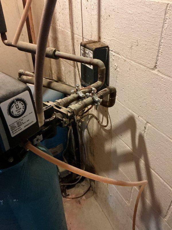 Installed new 100 amp meter base and disconnect on exterior service entrance. Modified PVC riser by cutting down and installing expansion coupling for proper clearance. Installed new grounding system with ground rods and verified existing waterline ground connection to panel. Established supplemental bonding by connecting to accessible copper piping in ceiling near tankless water heater, as unit is primarily served by PEX plumbing. Installed bonding jumpers around water softener system to maintain grounding continuity. Ran new 3-wire feeder circuit to main panel with PVC conduit protection along exterior wall within driveway proximity zone per code requirements. Corrected breaker compatibility issues in main panel by replacing incompatible tandem Siemens breaker with proper single-pole breaker and installing additional breaker in available space below. Removed incorrectly installed GE breaker and replaced with code-compliant Siemens 20 amp breaker matching panel specifications.