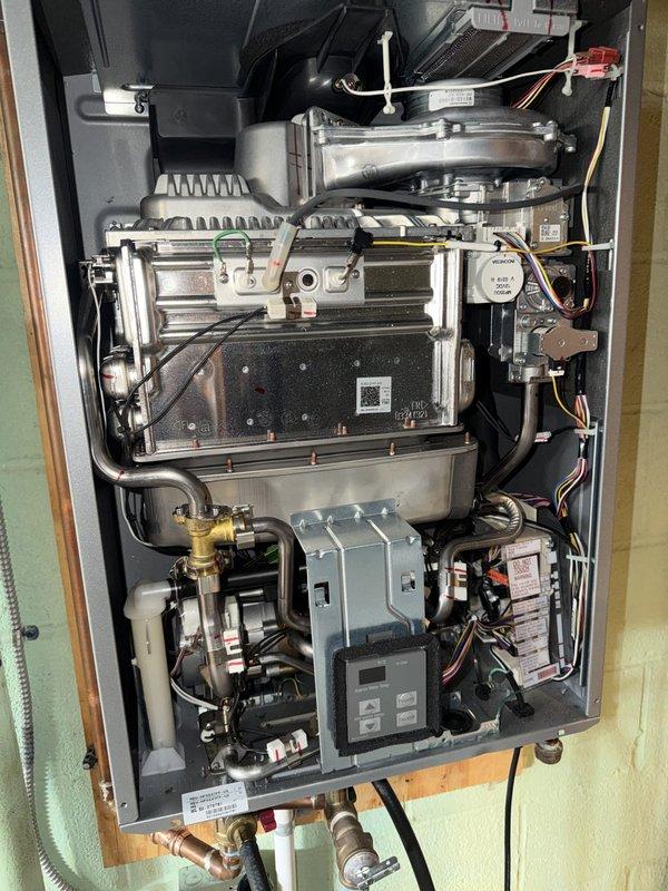 # Tankless Water Heater Flush - Rinnai Unit

Performed comprehensive flush and maintenance service on a Rinnai tankless water heater system in a 5-year-old residential property. The unit, installed in a basement utility area with proper venting and copper supply lines, was accessed and serviced according to manufacturer specifications.

## Work Performed

Isolated the tankless water heater by closing inlet and outlet service valves. Connected submersible pump and circulation hoses to the service ports using the existing isolation valve configuration. Prepared descaling solution and circulated through the heat exchanger assembly for the recommended duration to remove mineral buildup and scale deposits from the internal components.

Inspected the heat exchanger fins and burner assembly while the unit was open, verifying proper condition of the aluminum heat transfer surfaces. Examined the internal components including the fan assembly, gas valve, ignition system, and control board for an