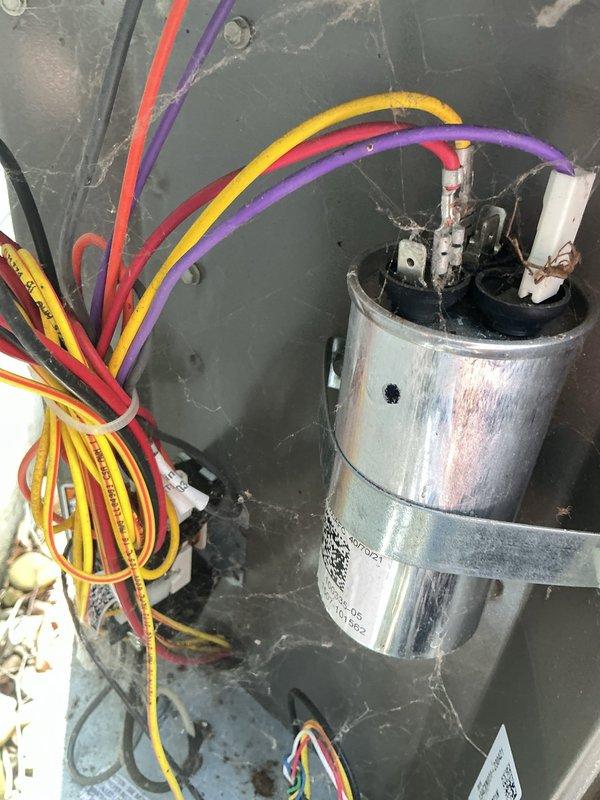 # HVAC Service Report - Water Leak Resolution

Responded to service call for water leaking through furnace from 11-year-old Lennox air conditioning system. Upon arrival, conducted thorough inspection of both indoor and outdoor equipment to identify source of water intrusion.

Exterior condenser unit inspection revealed significant accumulation of dirt, dust, and debris on internal surfaces and coil fins. Heavy grayish-brown grime buildup was observed on interior cavity walls between outer casing and evaporator coil, indicating extended period without maintenance. This level of contamination can restrict airflow and contribute to improper condensate drainage.

Opened access panel on outdoor unit to examine electrical components and internal condition. Inspected capacitor, wiring connections, and associated electrical terminals. All wire connections including yellow, red, purple, and black leads were checked for proper termination and secure mounting. Capacitor showed normal wear consist