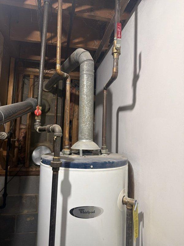 Responded to no hot water complaint and conducted on-site evaluation of existing Whirlpool tanked water heater installation in basement utility area. Inspected unit configuration, plumbing connections, safety strapping, and venting system to assess current condition and provide revised estimate options for replacement or repair. Documented equipment specifications and installation parameters with photographs for estimate preparation.
