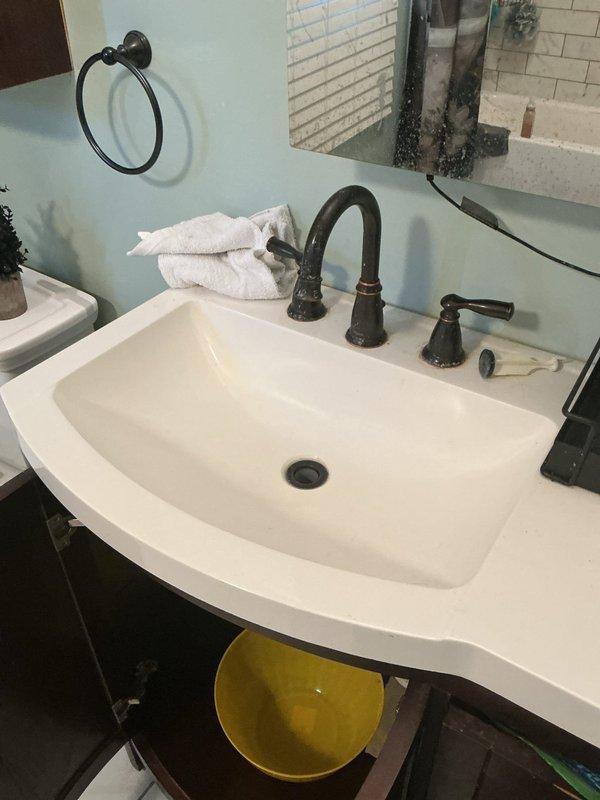 Responded to clogged bathroom sink in residential property. Upon arrival, assessed the undermount sink with bronze widespread faucet and dark wood vanity cabinet. Accessed the P-trap assembly beneath the sink and identified blockage in the drain line. Removed and disassembled the white PVC P-trap configuration, clearing accumulated debris and buildup causing the obstruction. Inspected flexible corrugated section and rigid plastic pipe segments for additional blockages. Cleaned all drain components thoroughly and reassembled the P-trap with proper slip-joint fittings to ensure watertight connections. Tested drain flow and verified proper drainage with no leaks detected at connection points. Left work area clean and plumbing system fully operational.
