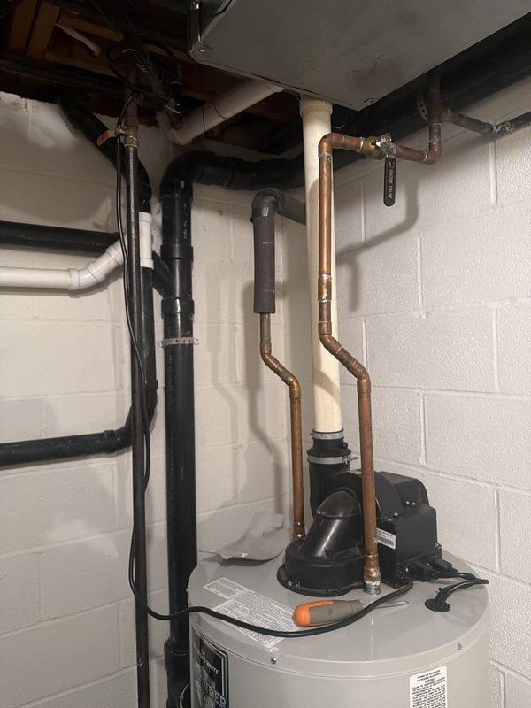 Responded to service call for leaking hot water tank causing property damage. Upon arrival, inspected existing water heater installation and confirmed active leak from aging unit. Documented current setup including power vent configuration with black pump assembly, copper supply lines, and gas connections. Photographed existing Bradford White installation showing vertical black vent piping, copper plumbing connections, and mounting configuration in utility area with concrete block walls. Assessed damage to surrounding area and noted water accumulation at base of unit. Provided detailed estimate for replacement with Bradford White 50-gallon gas tall power vent water heater to match existing specifications and venting requirements.