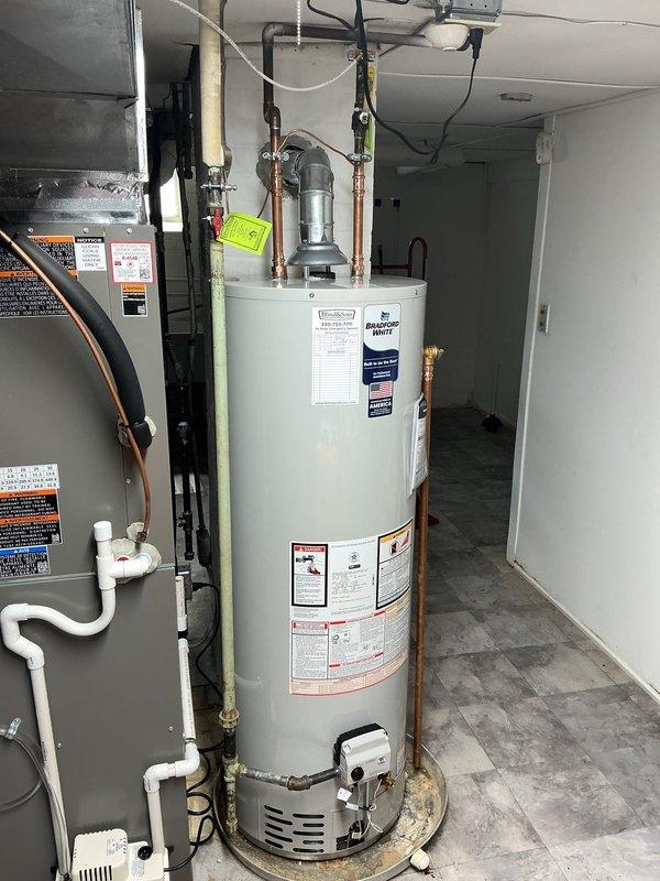 Installed a new 40-gallon Bradford White water heater with 6-year manufacturer warranty in residential utility room. Reused existing ball valve and expansion tank already present on the line after the meter. Removed, serviced, and reinstalled the boiler drain on the main water line using pipe thread sealant tape and dope to eliminate existing drip leak. All copper piping connections completed at top of unit with proper fittings, and installation verified for proper operation with adequate service access maintained around equipment.