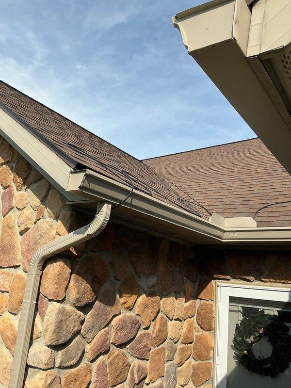 Installed two separate runs of roof heat tape on residential property: one above garage and adjacent section, and one on rear U-shaped roof section. Heat tape was properly installed in back-and-forth pattern along roof eaves and valleys, extending into gutters and down downspouts per manufacturer specifications. Connected first run to existing dedicated 20-amp circuit and second run to existing 15-amp circuit after verifying amperage calculations confirmed adequate capacity for safe operation.