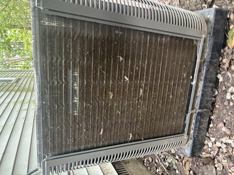 Performed MVP air conditioning maintenance on outdoor condensing unit. Inspected heat exchanger coil which showed significant accumulation of dirt, dust, leaves, and organic debris between fins, indicating extended service period without cleaning. Took electrical measurements using clamp meter, recording amperage readings of 27.7A and 25A to verify proper compressor and fan motor operation. Unit exhibited typical outdoor weathering patterns consistent with normal exposure conditions.