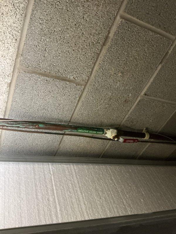 Responded to service call for reported hot water tank leak. Upon arrival, performed thorough inspection of plumbing system and identified source of water leakage. Documented existing copper piping with brass fittings in wall cavity and overhead copper pipe installation in drop ceiling area showing signs of oxidation and age-related deterioration. Assessed leak location and provided customer with findings and repair recommendations.