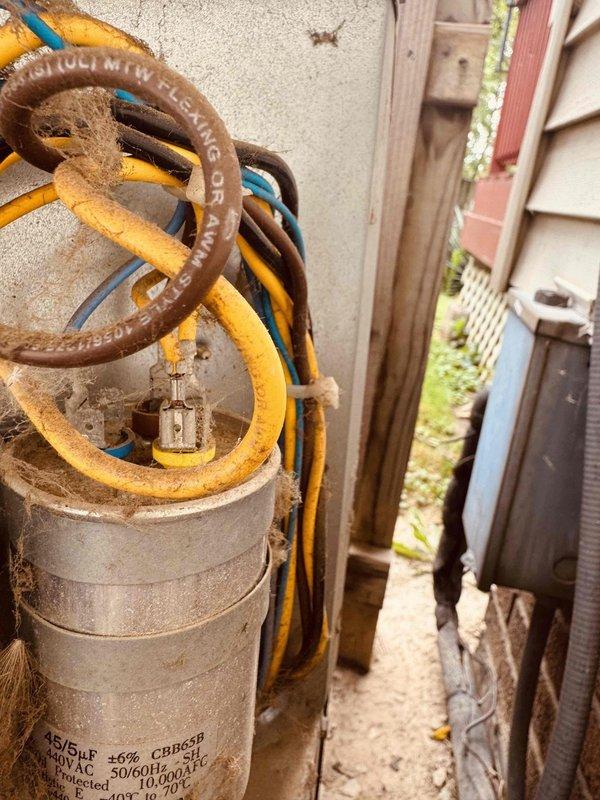 Responded to no cooling complaint on 8-year-old residential air conditioning system. Upon arrival, confirmed unit was running but delivering warm air to living space. Performed diagnostic testing on outdoor condensing unit and identified failed dual run capacitor. Capacitor showed visible signs of age, corrosion, and environmental exposure with heavy dirt and cobweb accumulation on component and surrounding electrical connections. Used Fieldpiece SC640 meter to verify capacitor failure with readings well below manufacturer specifications. Explained findings to customer and discussed repair versus replacement options given system age and overall condition of equipment. Customer expressed interest in system replacement but authorized immediate capacitor replacement to restore cooling. Replaced defective capacitor with properly rated OEM equivalent, verified all electrical connections, and tested system operation. Unit cycled properly with compressor and condenser fan motor running at cor