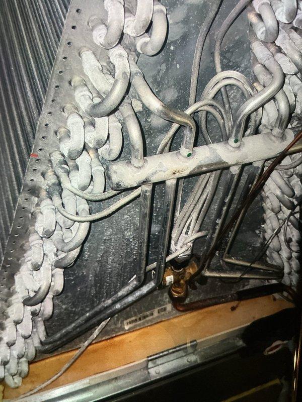Completed MVP cooling maintenance visit and comprehensive system inspection. Upon accessing the air handling unit, discovered evaporator coils exhibiting significant contamination with orange-brown discoloration indicating rust deposits, mineral buildup, and potential microbial growth on coil surfaces. The diamond mesh pattern coils showed extensive staining across both vertical and horizontal sections, compromising heat transfer efficiency.

Further inspection revealed severe frost and ice accumulation on refrigerant coils in a serpentine configuration, completely encasing the U-shaped copper tubing. This abnormal frost buildup indicates restricted airflow from the contaminated evaporator coils and possible low refrigerant charge or metering device malfunction. Documented all findings with photographic evidence showing the extent of coil contamination and frost formation throughout the system.

Inspected refrigerant lines, brass fittings, and condensate drainage system including the r