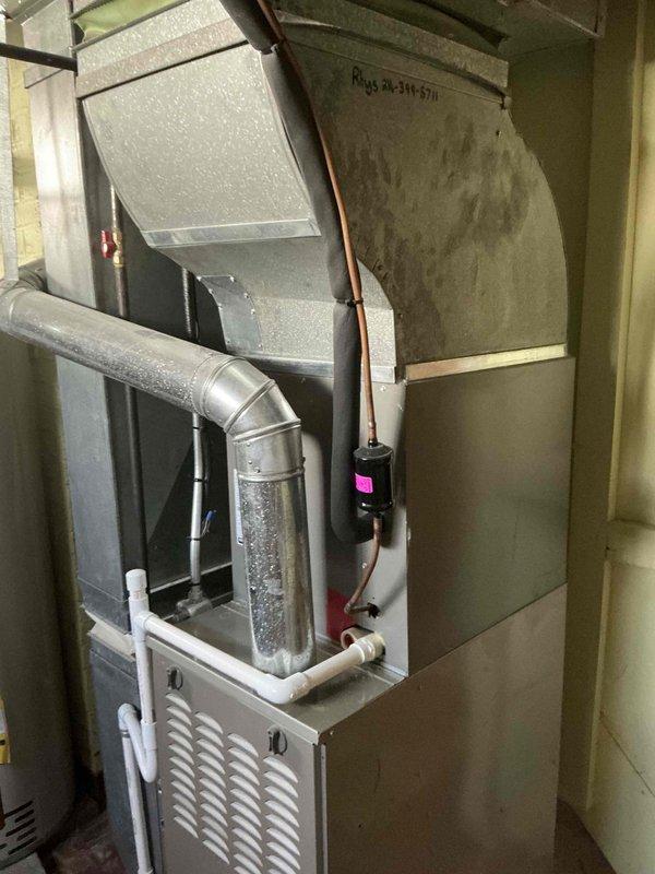 Completed furnace replacement estimate for 12-year-old unit with failed motor. Evaluated existing Carrier furnace system in basement utility area with associated ductwork, refrigerant lines, and condensate drainage. Documented current installation including vertical air handler configuration, insulated plenum, sheet metal distribution ductwork, and copper refrigerant piping for replacement quotation purposes.