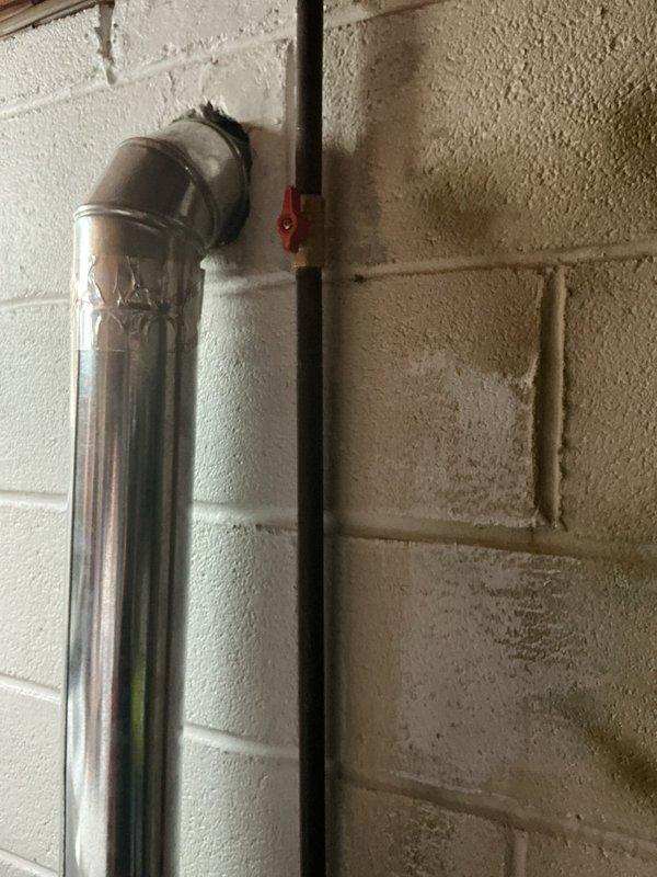 Responded to service call for shut-off valve evaluation in residential utility space. Inspected existing plumbing configuration consisting of vertical chrome pipe with elbow joint connecting to insulated horizontal pipe section and vertical black pipe with red valve handle mounted against painted cinderblock wall. Documented current valve condition and piping layout with photographs for estimate preparation. Provided customer with assessment for complete shut-off valve replacement.
