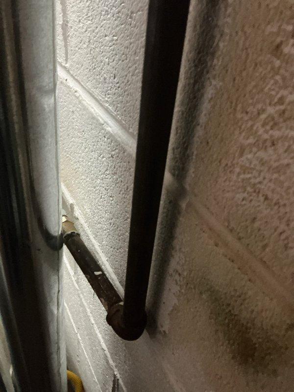 Responded to service call for shut-off valve evaluation in residential utility space. Inspected existing plumbing configuration consisting of vertical chrome pipe with elbow joint connecting to insulated horizontal pipe section and vertical black pipe with red valve handle mounted against painted cinderblock wall. Documented current valve condition and piping layout with photographs for estimate preparation. Provided customer with assessment for complete shut-off valve replacement.