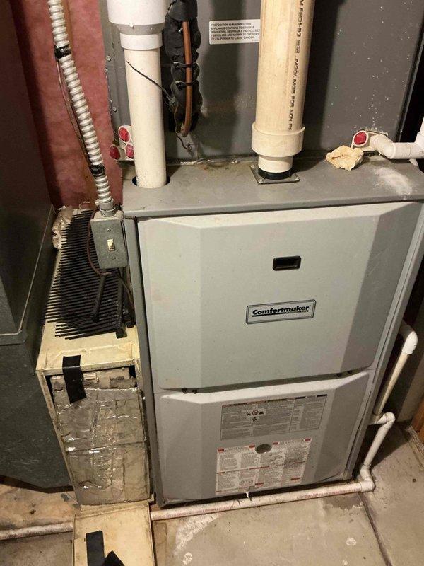 Conducted comprehensive HVAC estimate for air conditioning replacement at residential property. Evaluated existing Comfortmaker furnace system and associated components including humidifier, ductwork, and electrical connections in basement utility area. Documented current installation configuration with detailed photography showing furnace unit, PVC drainage lines, copper refrigerant lines, flexible ductwork, and electrical wiring for replacement planning purposes.